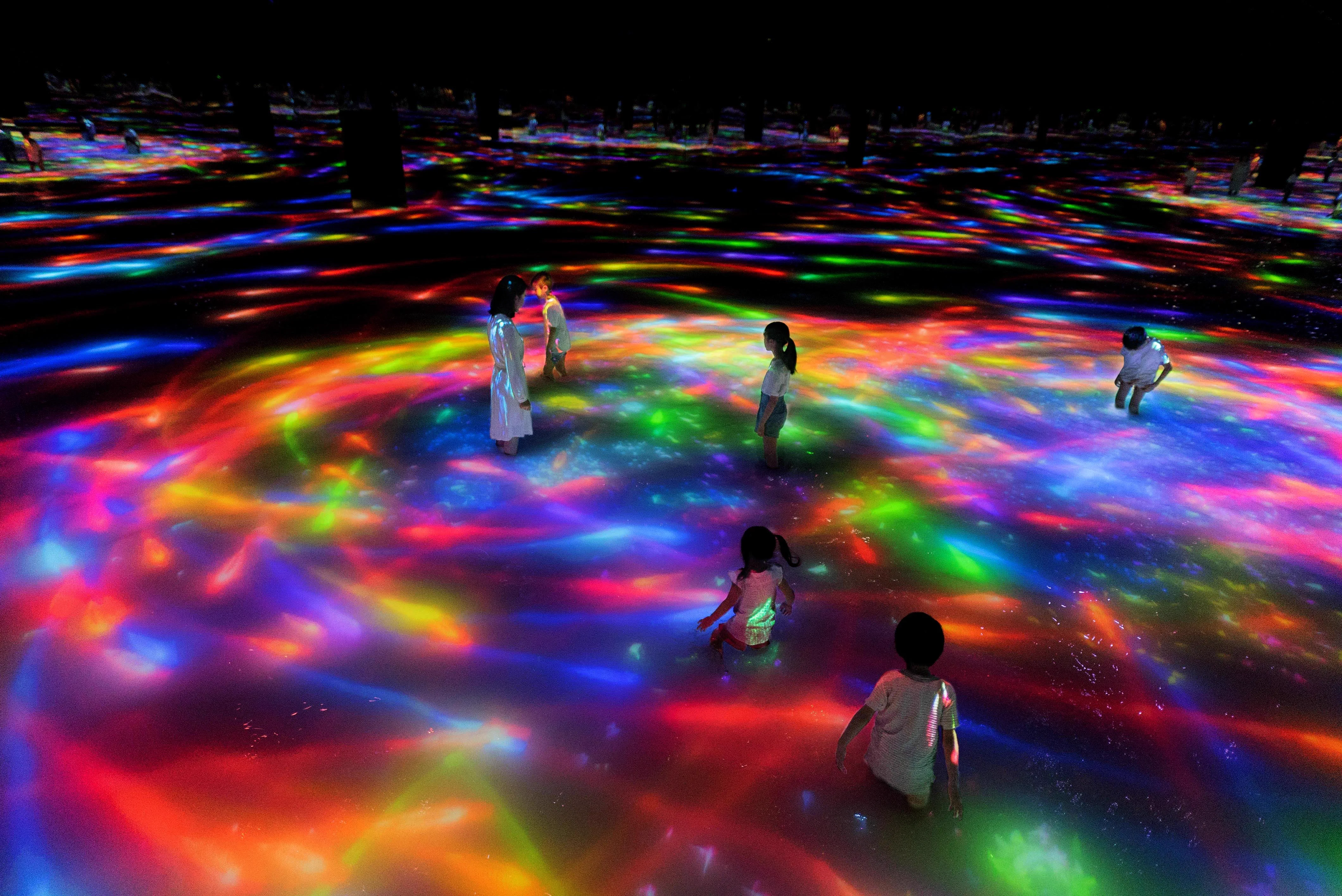 teamLab Planets 잉어와 사람이 함께 만드는 수면 작품에서 관람객이 맨발로 물속을 걷는 모습