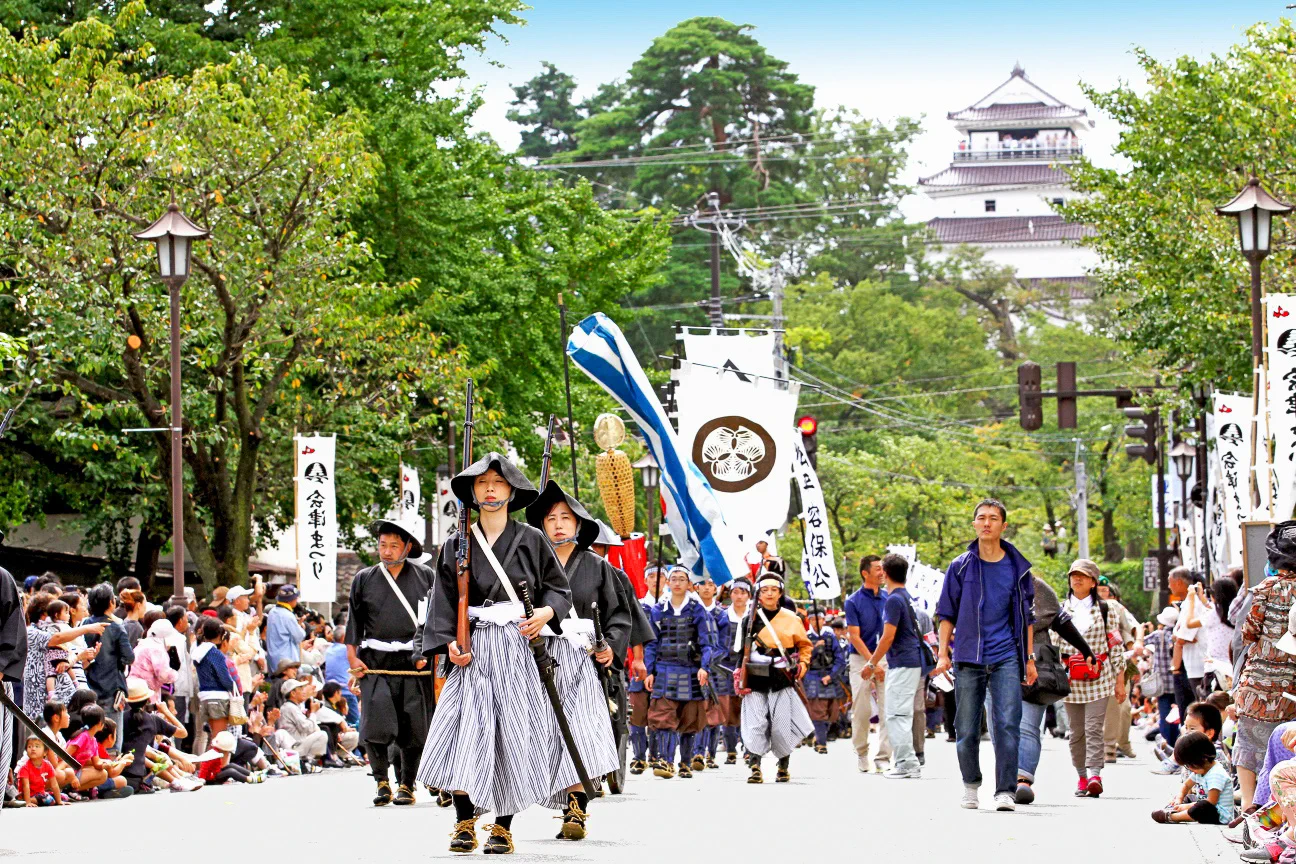 2026 아이즈 마쓰리 무사 행렬과 쓰루가성, 9월 축제 기간 혼마루 인파와 교통 변수를 보여 주는 장면